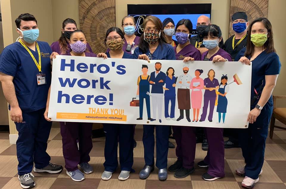 A group of nurses holding a sign that says hero's work here.