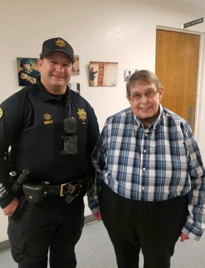 A police officer and an elderly man standing next to each other.